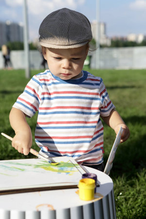 Boy drawing gouache in a summer parkの写真素材