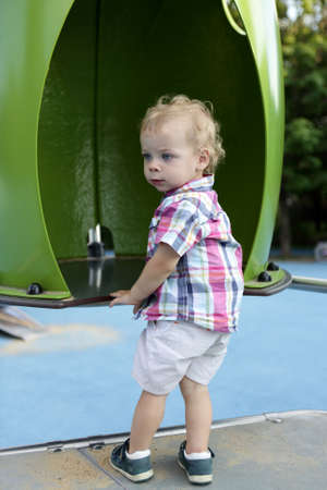 Curly toddler standing at playground in summerの写真素材