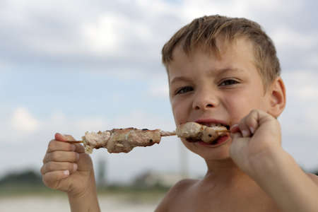 Kid eating kebab on a beach in summerの写真素材