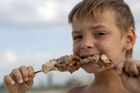 Child eating kebab on a beach in summerの写真素材