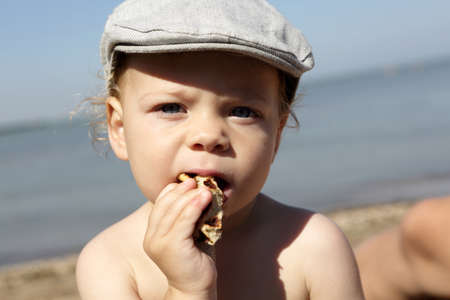 Toddler eating pancake on a beach in summerの写真素材