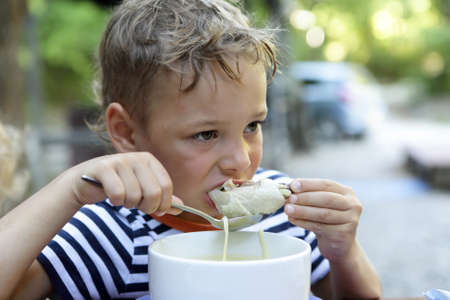 Kid eating chicken soup in a restaurantの写真素材