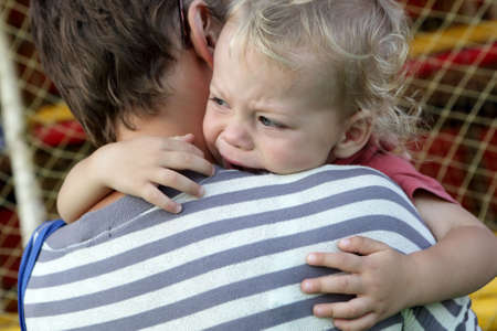 Child crying on mother shoulder in summer