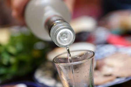 Person pouring vodka into glass at restaurant