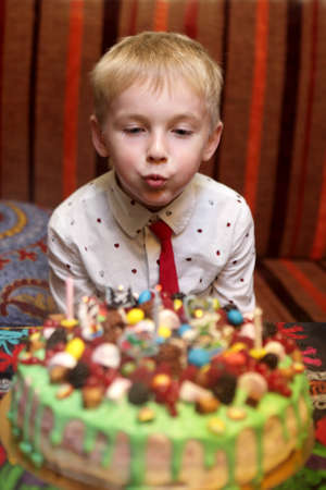 Child blowing out candles on birthday cake in cafeの写真素材