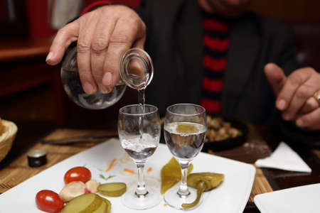 Person filling glass of vodka in a pub