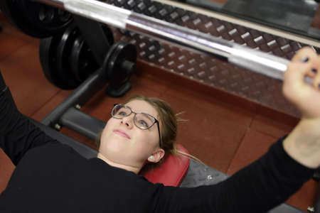 Teen lifting barbell with weight in a gym