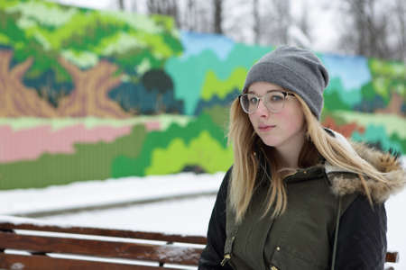 Portrait of a thinking teen on bench in winterの写真素材