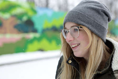 Portrait of a smiling teen in glasses on bench in winterの写真素材