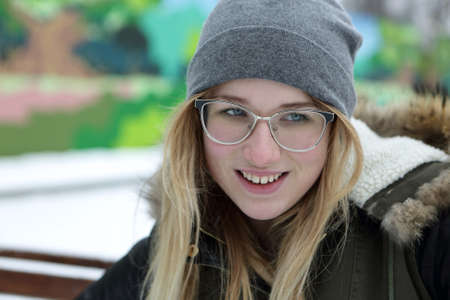 Portrait of a smiling teenager on bench in winterの写真素材