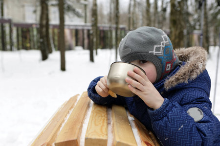 Kid drinking tea in a winter parkの写真素材