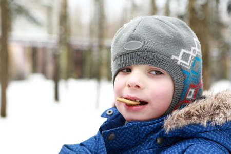 Kid eating biscuit in a winter park