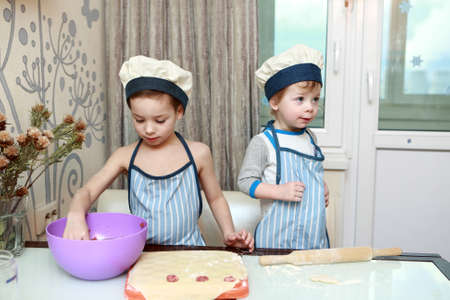 Two Kids mold dumplings in kitchen at homeの写真素材