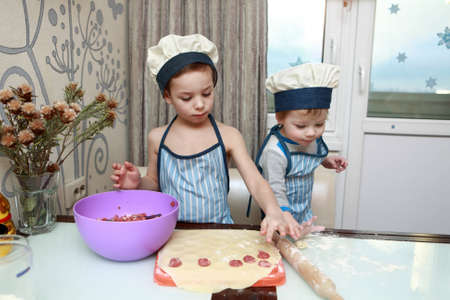 Two serious boys mold dumplings in kitchen at homeの写真素材