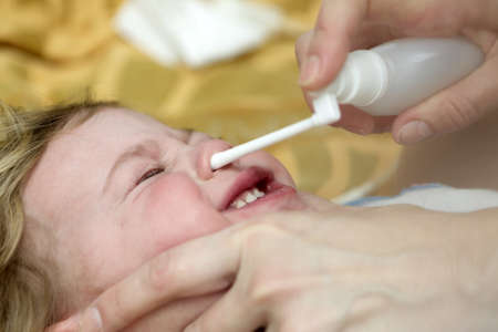 Kid Inhaling Nasal Spray on bed at home