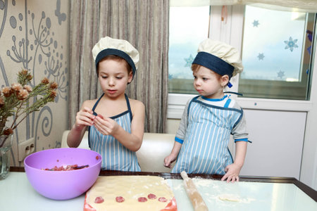 Two serious children mold dumplings in kitchen at homeの写真素材