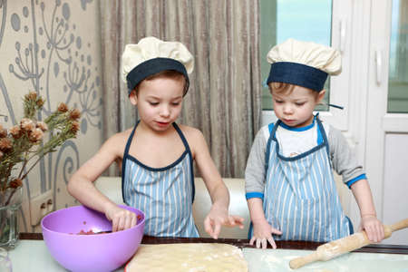Two Children mold dumplings in kitchen at homeの写真素材