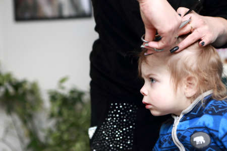 Serious boy having a haircut first time at the barbershopの写真素材