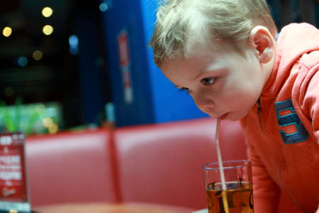 Child drinking apple juice in a cafeの写真素材