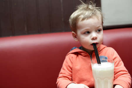 Child drinking milkshake on sofa in cafe