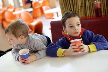 Two children drinking juice at fast food courtの写真素材