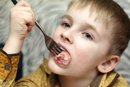Pensive boy eating sausage in a cafeの写真素材