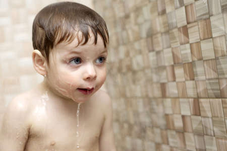 Thinking kid takes a shower in a bath houseの写真素材