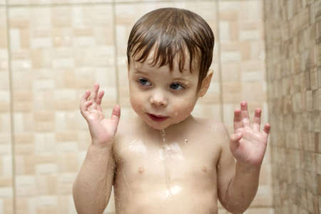 Thinking boy takes a shower in a bath houseの写真素材