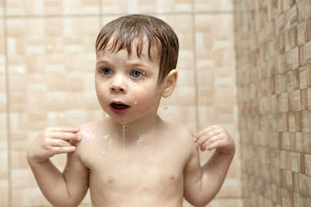 Surprised boy takes a shower in a bath houseの写真素材
