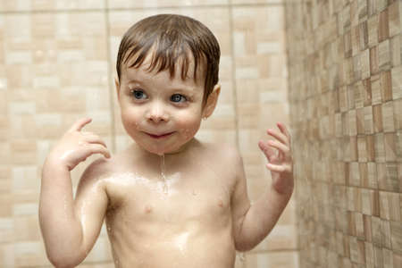 Happy boy takes a shower in a bath houseの写真素材