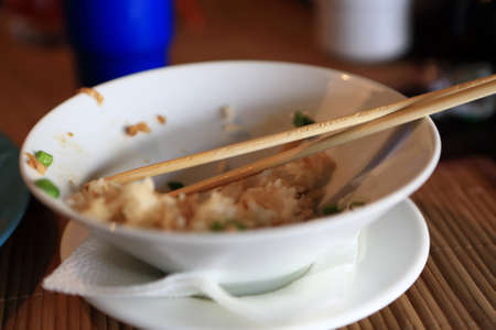 Leftovers of rice and chopsticks in the plateの写真素材