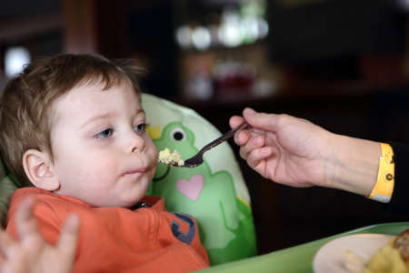 Mother feeding her son omelet in cafeの写真素材