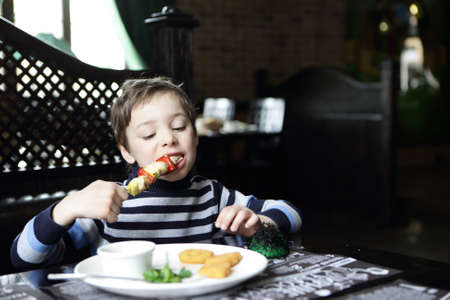 Hungry child eating kebab in a restaurantの写真素材