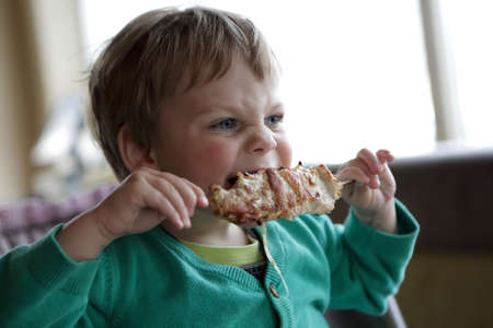 Boy eating kebab on stick in a cafe
