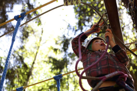 Kid climbing in rope park in forest
