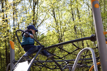 Boy climbing in playground at summer parkの写真素材