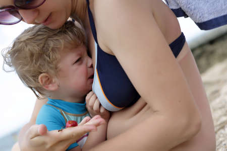 Portrait of crying child on his mother handsの写真素材