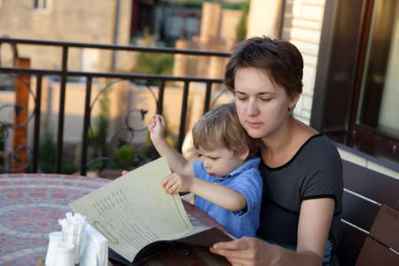 Mother with her son holding menu in a cafeの写真素材