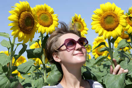 Woman posing with sunflowers on the fieldの写真素材