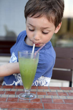 Kid has fruit smoothies in a cafeの写真素材