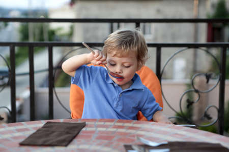 Hungry child has lunch in a restaurantの写真素材