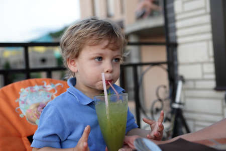 Boy has fruit smoothies in a cafeの写真素材