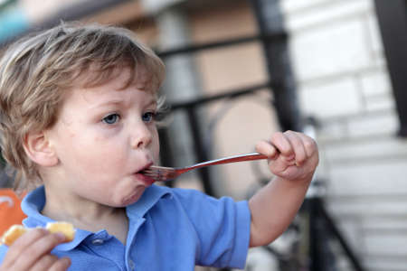 Hungry boy has lunch in a restaurantの写真素材
