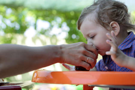 Child drinking juice fron his mother handの写真素材