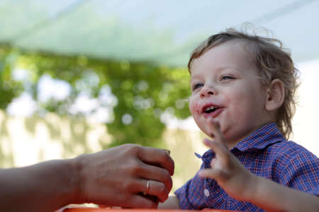 Boy drinking juice fron his mother handの写真素材
