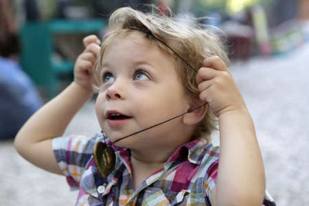 Child puts on amulet in summer park