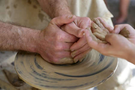 Potter helping a kid making a pottery