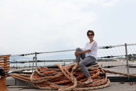 Woman sitting on the rope in deck of ship