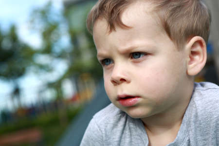 Portrait of a serious boy outdoor in summer