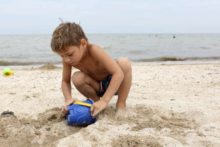 Boy playing with toy bucket on the beachの写真素材